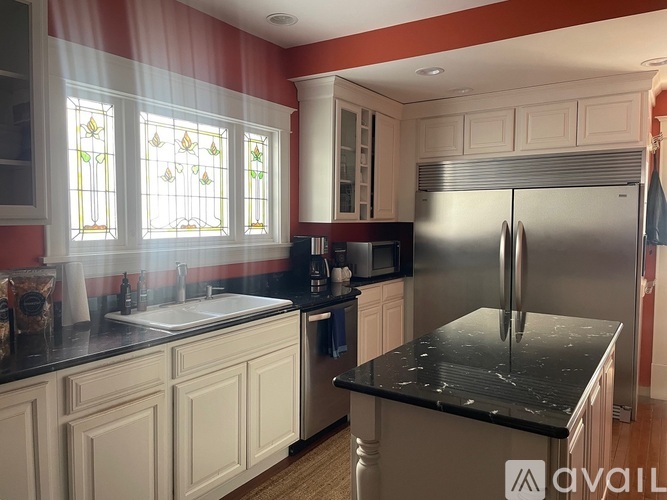 A kitchen with a black countertop and a stainless steel refrigerator.