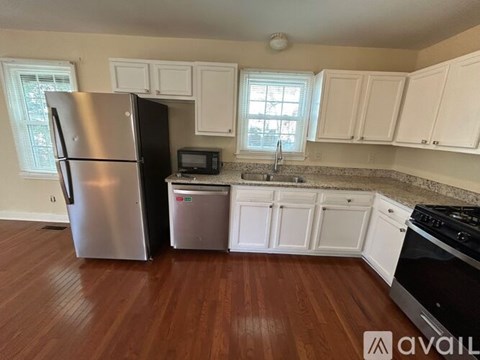 A kitchen with white cabinets and a stainless steel refrigerator.