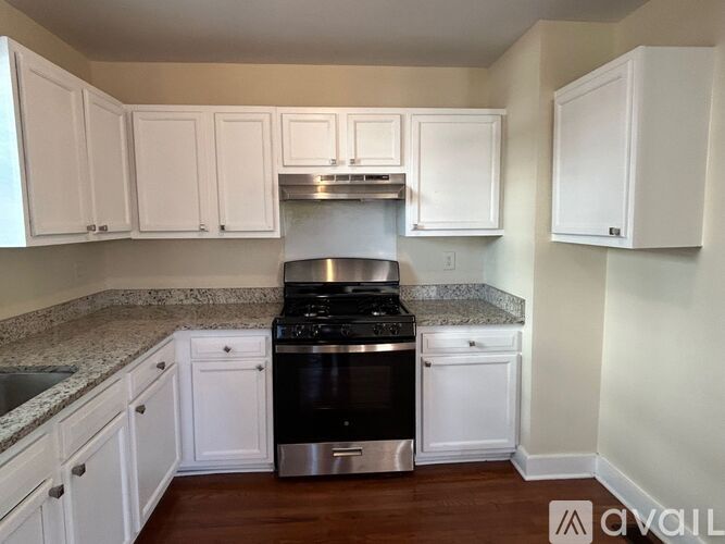 A kitchen with white cabinets and a granite countertop.