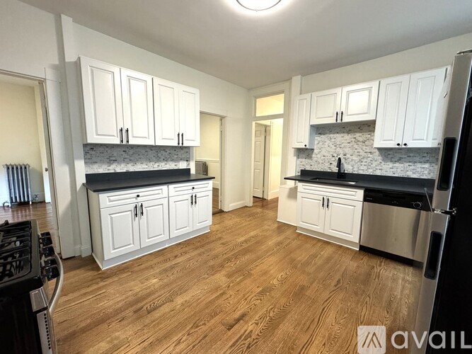 A kitchen with white cabinets and a wooden floor.