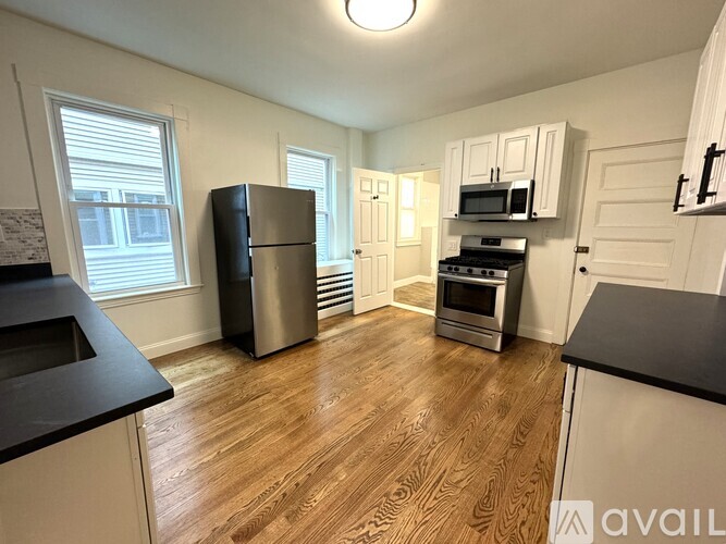 A kitchen with wooden floors and white cabinets.