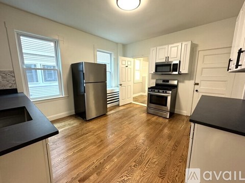 A kitchen with wooden floors and white cabinets.