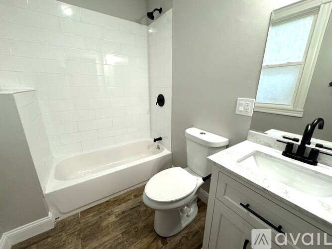 A white toilet sits in a bathroom with a white tub and sink.