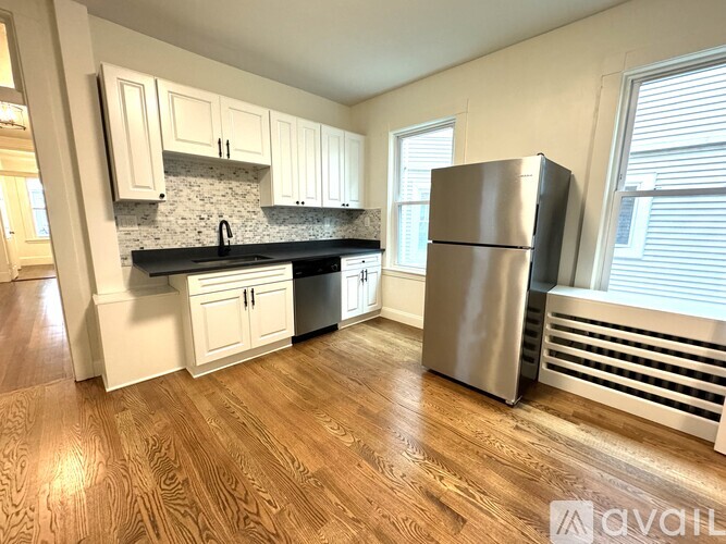 A kitchen with wooden floors and a stainless steel refrigerator.