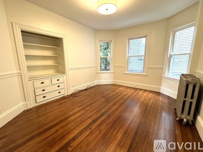 A room with wooden flooring and a window with blinds.