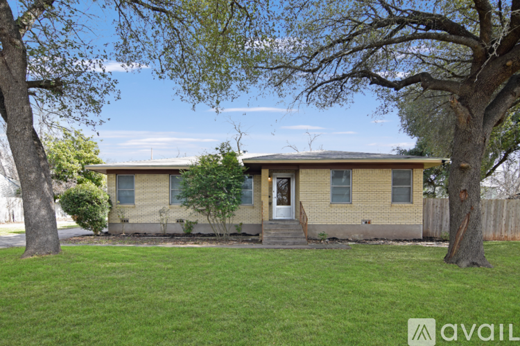 A house with a green lawn and trees in front.