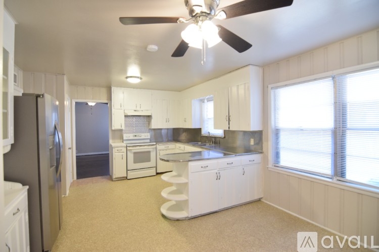 A kitchen with white cabinets and a fan on the ceiling.