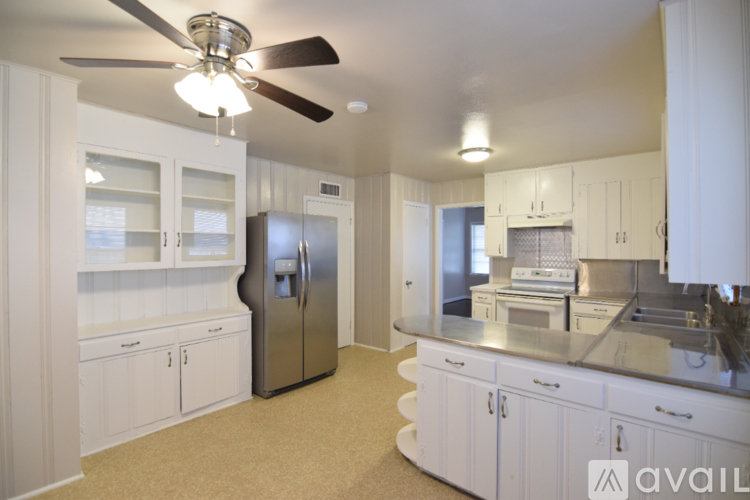 A kitchen with white cabinets and a stainless steel refrigerator.
