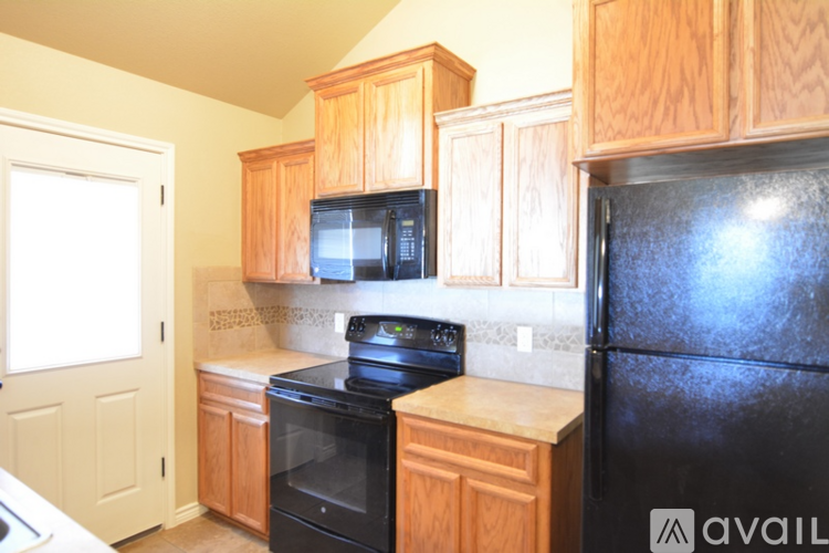 A kitchen with wooden cabinets and a black refrigerator.