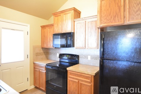 A kitchen with wooden cabinets and a black refrigerator.