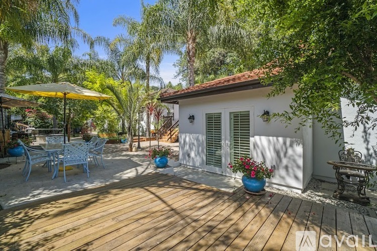 A patio with a table and chairs is surrounded by trees.