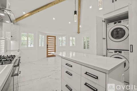A modern kitchen with white cabinets and a marble countertop.