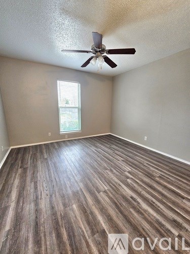 A room with a ceiling fan and wooden flooring.