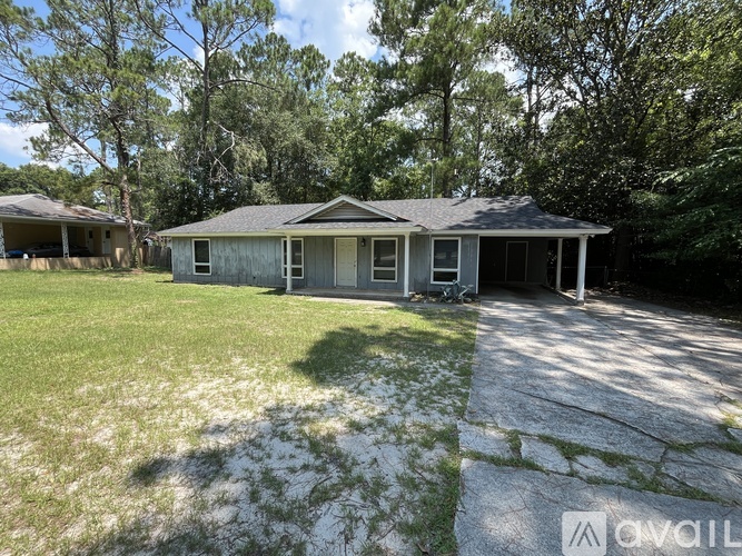 A house with a grey roof and a white garage door is surrounded by trees.