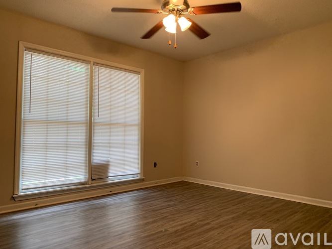 A room with a ceiling fan and two windows with blinds.