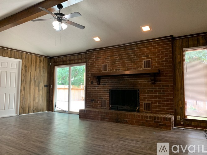 A living room with a brick fireplace and a ceiling fan.