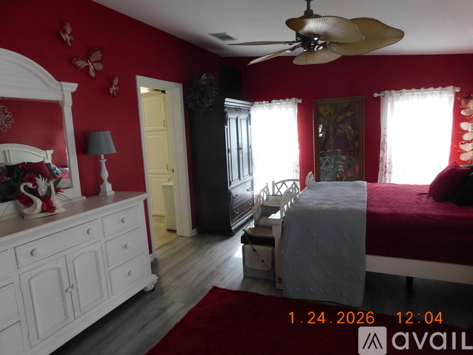 A bedroom with red walls and a white dresser.