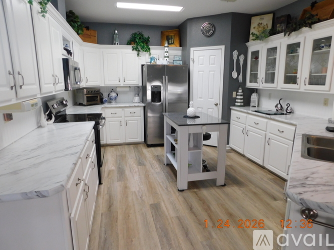A kitchen with white cabinets and a marble countertop.