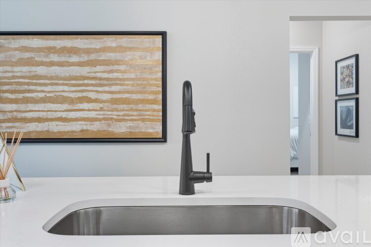 A modern kitchen with a stainless steel sink and a painting on the wall.