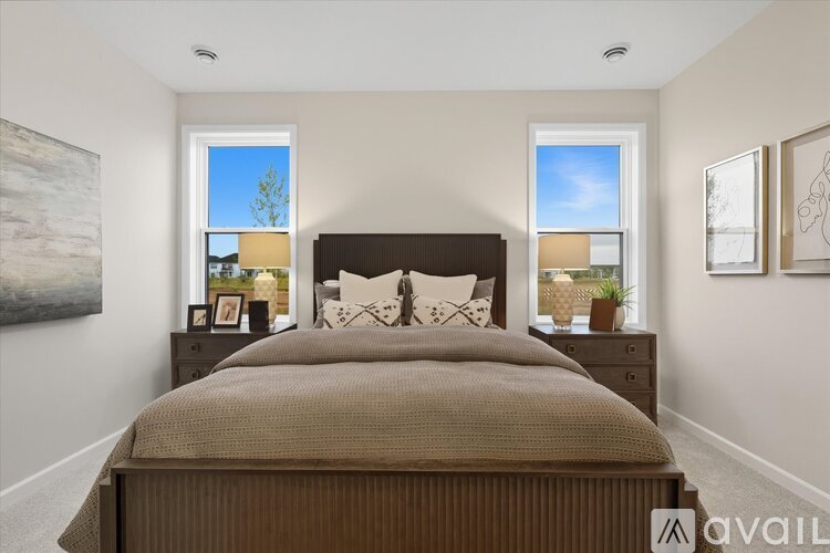A bedroom with a large bed and two windows.