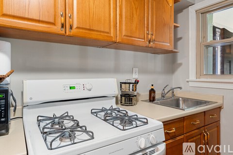 A kitchen with a white stove and wooden cabinets.