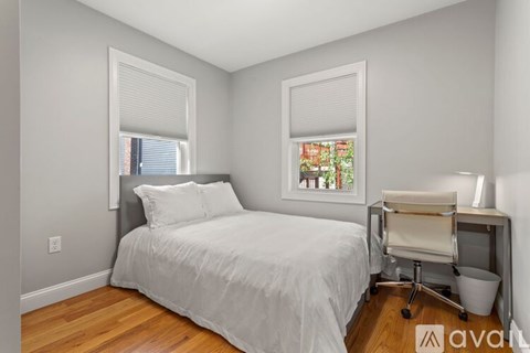 A bedroom with a bed, chair, and window.