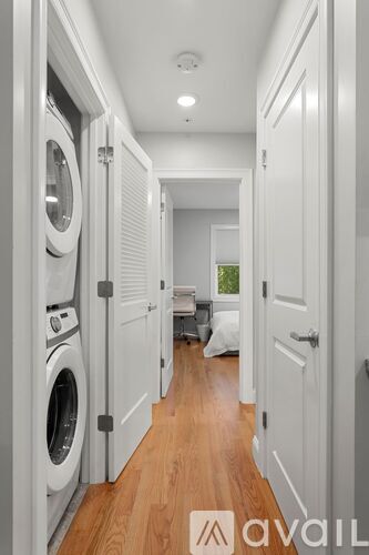 A hallway with a washer and dryer on the left and a door on the right.