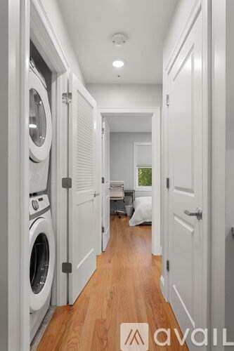 A hallway with a washer and dryer on the left and a door on the right.