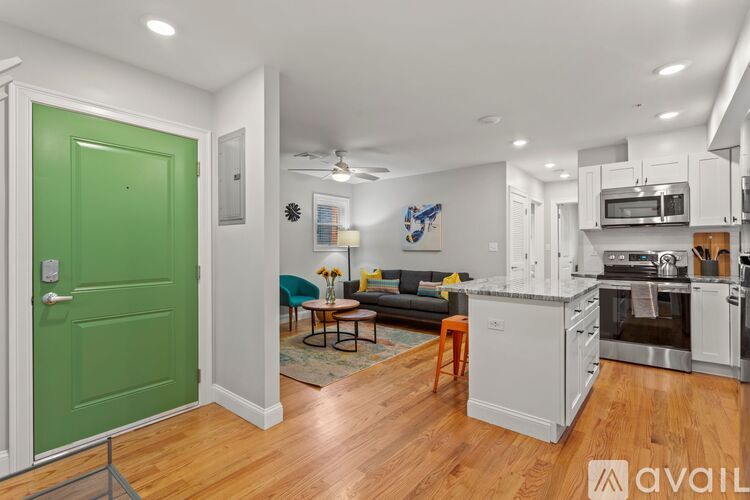 A kitchen with a green door and wooden floors.