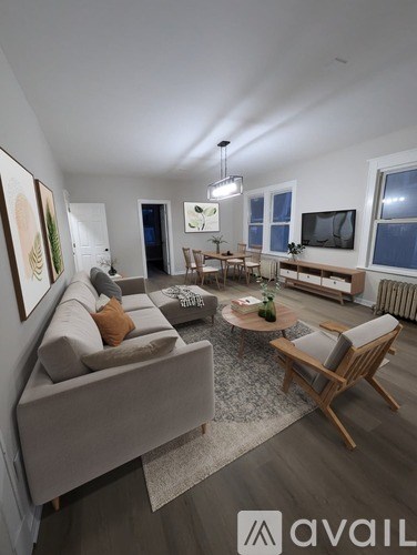 A living room with a grey couch and wooden chairs.
