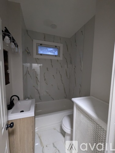 A bathroom with a white tub, sink, and toilet.