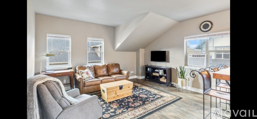 A living room with a grey couch, a brown leather couch, a wooden coffee table, a television, and a large window.