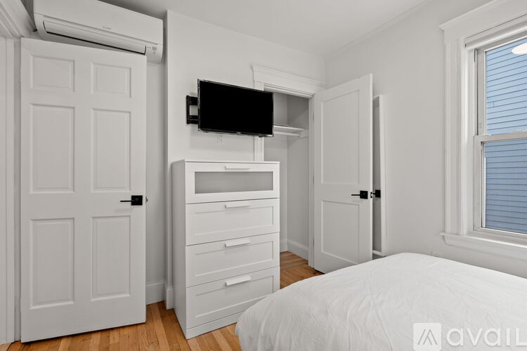 A bedroom with a bed, dresser, and a television mounted on the wall.