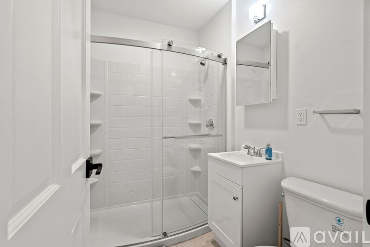 A white bathroom with a walk in shower and a white sink.
