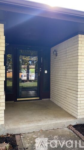 The entrance to a building with a glass door and a wall on the right side.