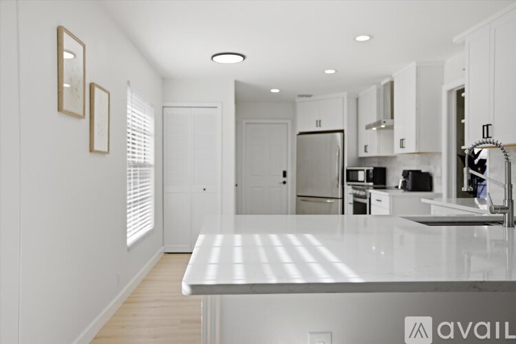 A kitchen with white cabinets and a white island.
