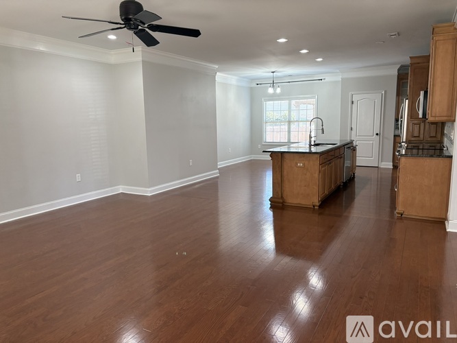 A spacious room with wooden floors and a ceiling fan.