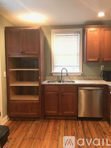 A kitchen with wooden cabinets and a stainless steel dishwasher.