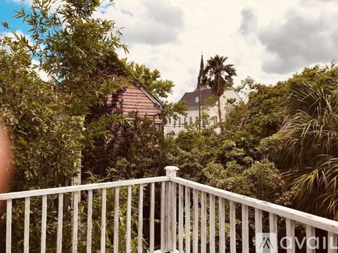 A white fence in front of a house with a church in the background.