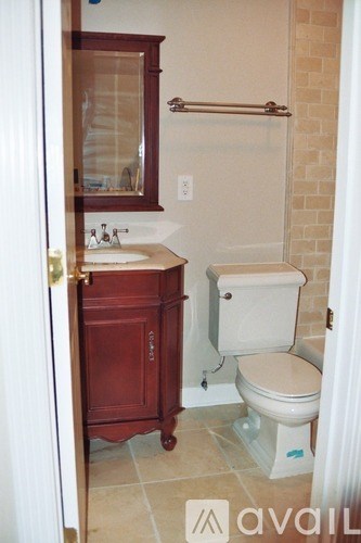 A bathroom with a toilet, sink and cabinet.