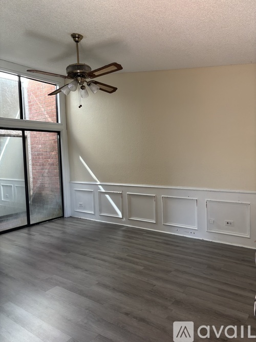 A room with a ceiling fan and a sliding glass door.