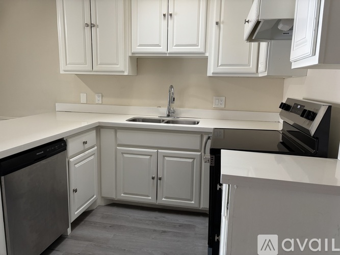 A modern kitchen with white cabinets and a black dishwasher.