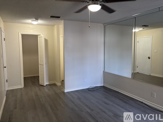 A spacious room with a ceiling fan and a large mirror on the wall.