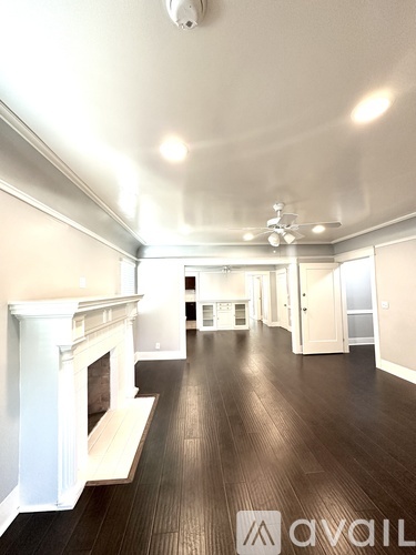 A spacious living room with a fireplace and a ceiling fan.