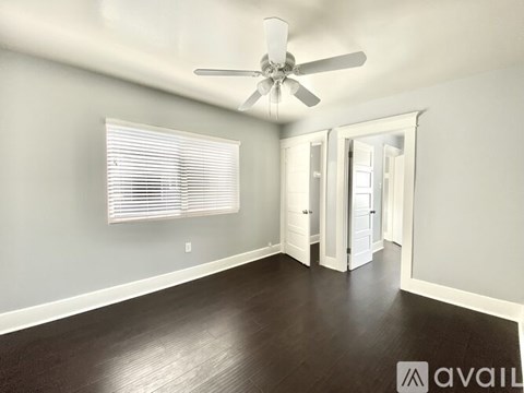 A room with a ceiling fan and wooden flooring.
