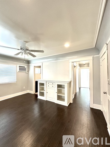 A spacious room with wood flooring and a ceiling fan.