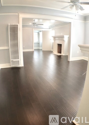 A spacious room with wood flooring and a ceiling fan.