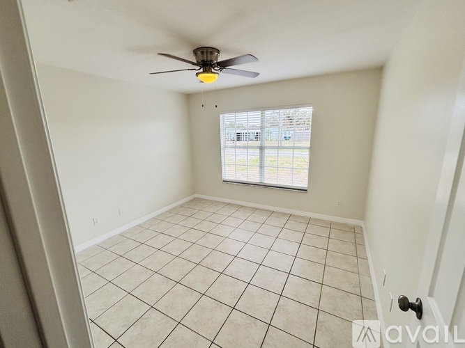 A room with a ceiling fan and a window with blinds.