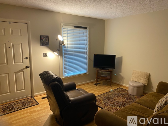 A living room with a brown couch, a black leather chair, and a television on a stand.
