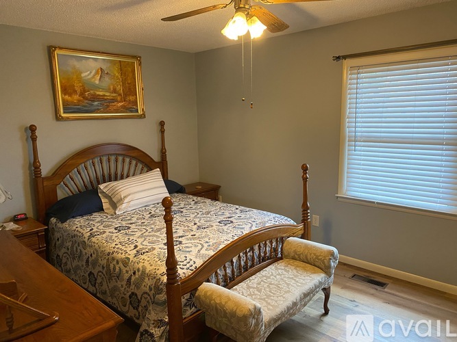 A bedroom with a bed, chair, and painting on the wall.